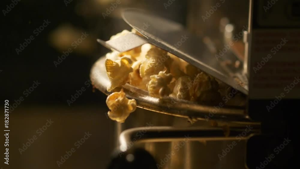 Fresh roasted pop corn pop out of the bowl - pop corn maker in a movie theater