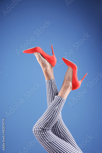 Young woman in stylish shoes on color background