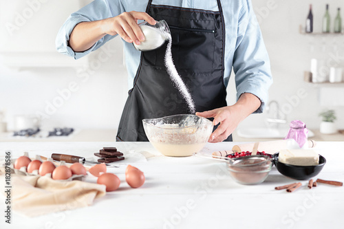 A cook with eggs on a rustic kitchen against the background of men's hands