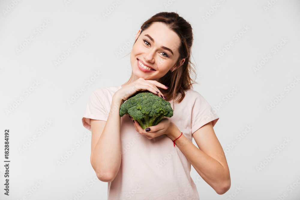 Portrait of a smiling pretty girl holding broccoli Portrait of a smiling pretty girl holding broccoli