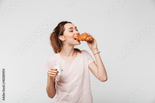 Portrait of a happy pretty girl eating croissant