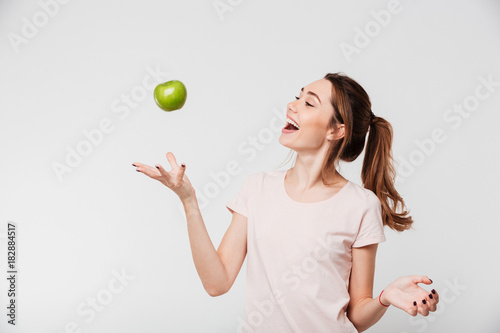 Fototapeta Portret uśmiechniętej dziewczyny miotania jabłko w powietrzu
