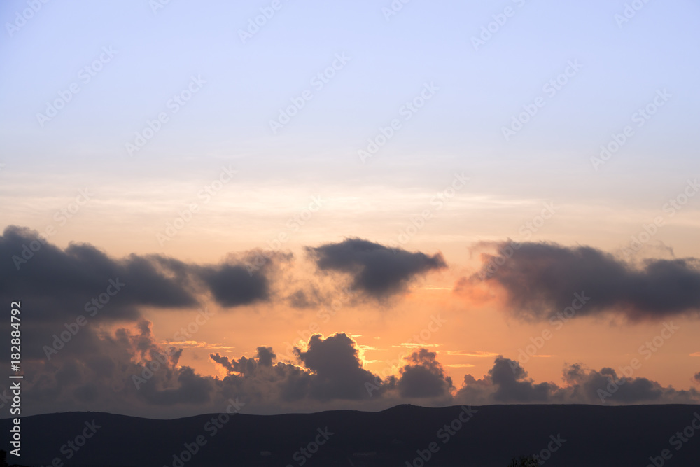 Colorful dawn/dusk sky with dark clouds background.