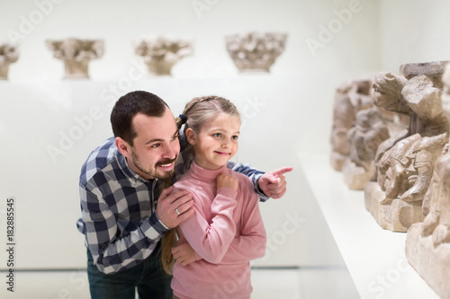 Father and daughter looking at ancient bas-reliefs in museum photo