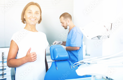Girl is standing satisfied  in dental office
