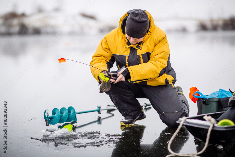 Man ice fishing on a frozen lake.