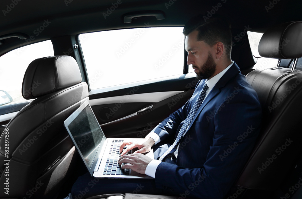 businessman using a laptop in the backseat of a car businessman using a laptop in the backseat of a car