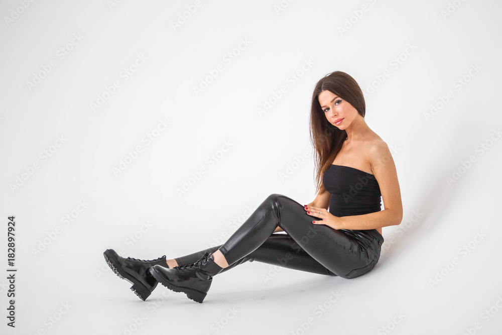 Beautiful girl brunette posing in black pants and top on a white background Beautiful girl brunette posing in black pants and top on a white background
