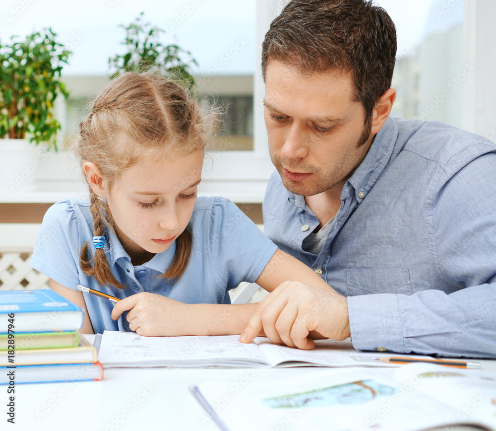 Father helping daughter with homework at home. Father helping daughter with homework at home.