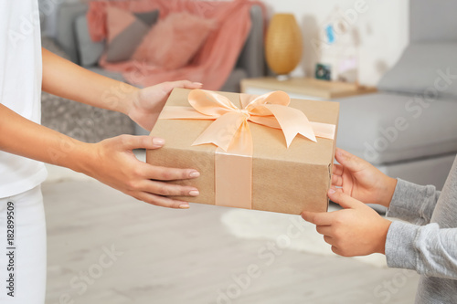 Young woman receiving Mother's Day gift from her little son at home, closeup