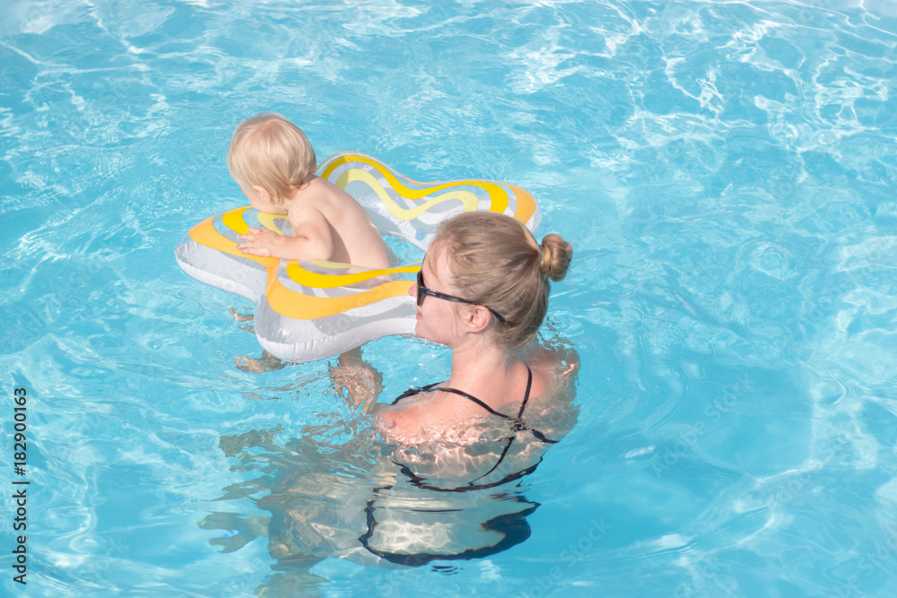 young mother with one year kid swim in blue pool and having good time young mother with one year kid swim in blue pool and having good time