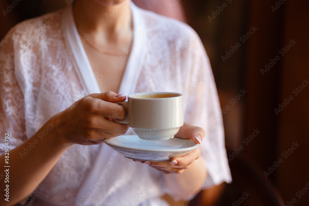 Young girl in Bathrobe with a pattern, drinking coffee on the hotel balcony, enjoying the view and the awakening. Morning girl drinking espresso. Close-up view. Young girl in Bathrobe with a pattern, drinking coffee on the hotel balcony, enjoying the view and the awakening. Morning girl drinking espresso. Close-up view.