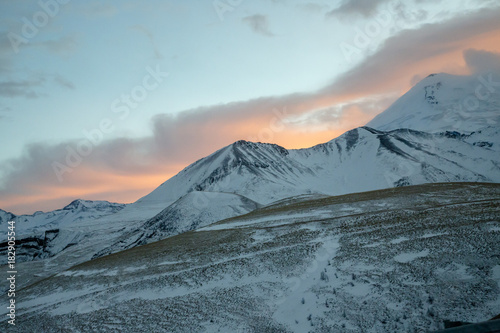 Fototapeta Naklejka Na Ścianę i Meble -  Зимний закат над снежными горами, красивые цвета на облачном небе, заход солнца, природа Северного Кавказа