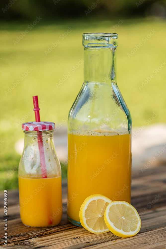 freshly sqeezed orange juice in a glass bottle outdoor shot in a garden freshly sqeezed orange juice in a glass bottle outdoor shot in a garden