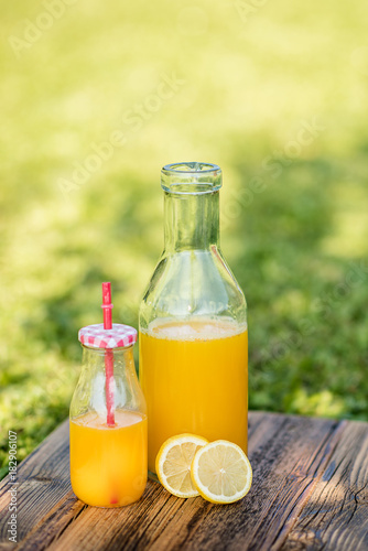 freshly sqeezed orange juice in a glass bottle outdoor shot in a garden