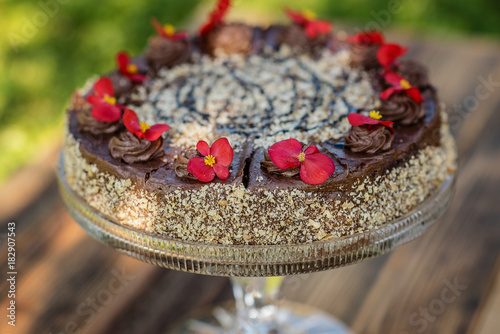 chocolate cake decorated with red eadible flowers photo