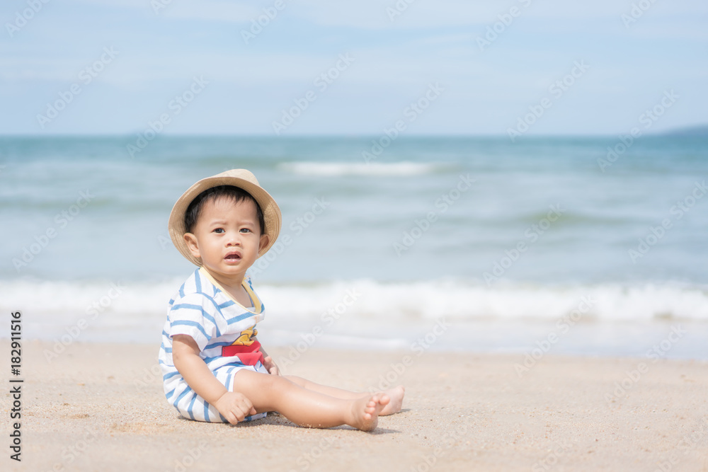Portrait of a 10 months Asian baby boy with a hat sit in beach near sea in Phuket, Thailand. Summer, vacation, Travel and Holiday concept.. Portrait of a 10 months Asian baby boy with a hat sit in beach near sea in Phuket, Thailand. Summer, vacation, Travel and Holiday concept..
