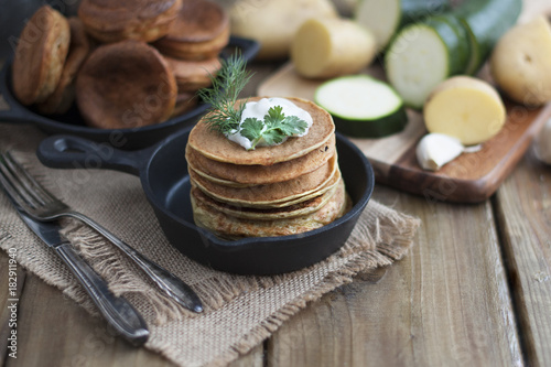 pancakes from vegetables in a cast-iron frying pan on a wooden background