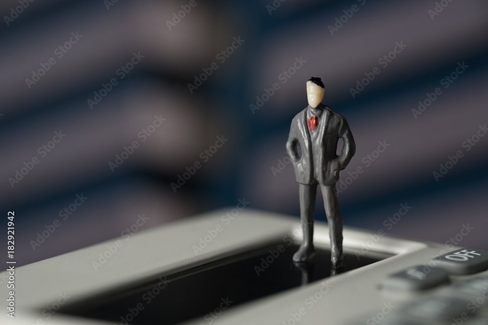 Figure miniature businessman or small people standing on calculator for money and financial business concept. Figure miniature businessman or small people standing on calculator for money and financial business concept.