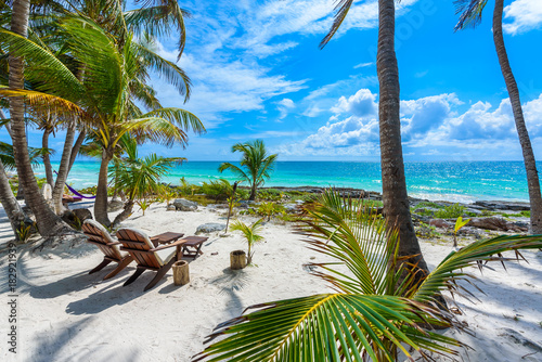 Chairs under the palm trees on paradise beach at tropical Resort. Riviera Maya - Caribbean coast at Tulum in Quintana Roo, Mexico