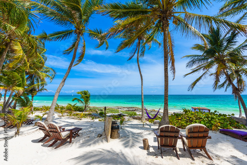Chairs under the palm trees on paradise beach at tropical Resort. Riviera Maya - Caribbean coast at Tulum in Quintana Roo, Mexico photo