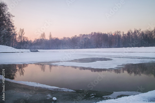 Winter sunset on the frozen lake in park