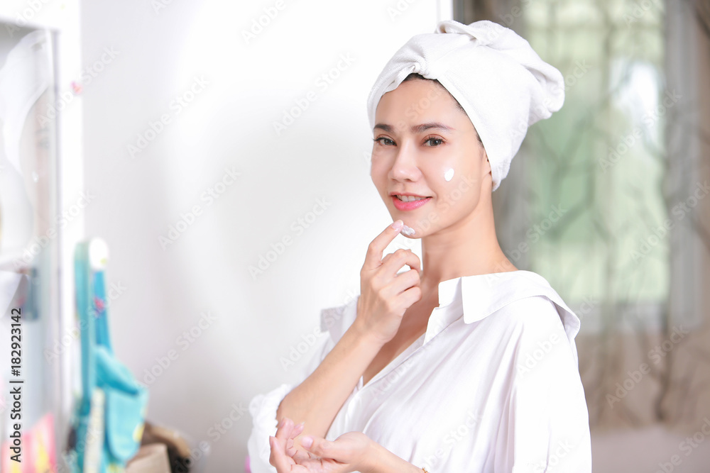 Young woman applying cream to face mirror reflection at dressing room. Young woman applying cream to face mirror reflection at dressing room.