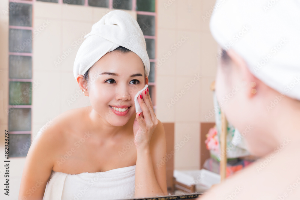 Beautiful woman removing makeup from her face in bathroom. Beautiful woman removing makeup from her face in bathroom.