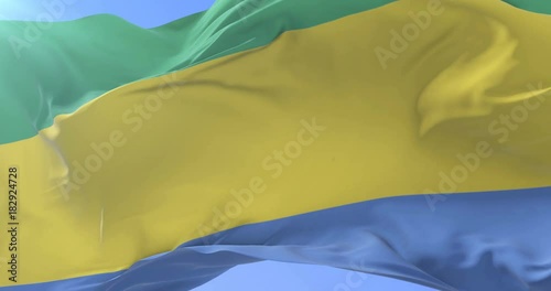 Gabonese flag waving at wind with blue sky in slow, loop photo