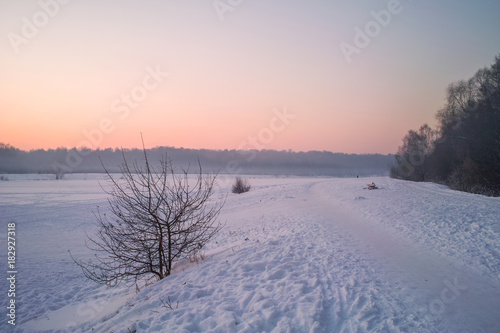 Winter sunset on the frozen lake in park