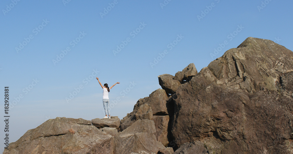 Woman hiker standing on rock on top of hill Woman hiker standing on rock on top of hill