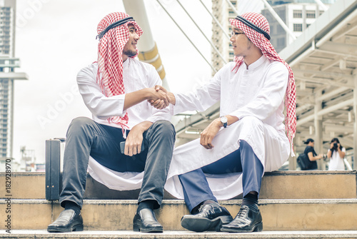 The new life for the city. Two Arabic muslim are shaking hands on cityscape background, Business Successful concept,