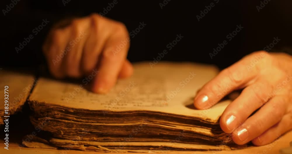 Elderly woman reading old book by candlelight

