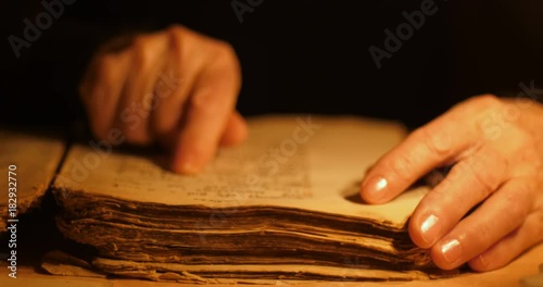 Elderly woman reading old book by candlelight

