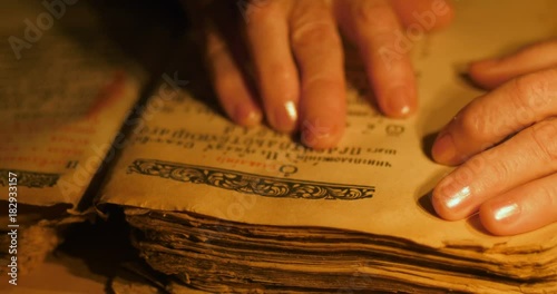 Elderly woman reading old book by candlelight

