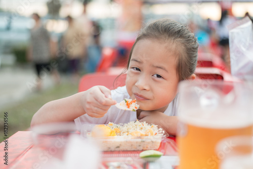 Happy asian kid girl eat street food in thailand