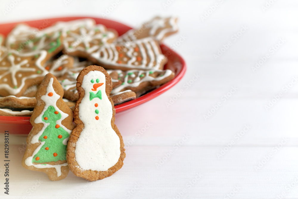 fun atmosphere of winter holidays/ ginger cookies in the shape of Christmas tree and funny snowman stands on table in red plate full of different pastries