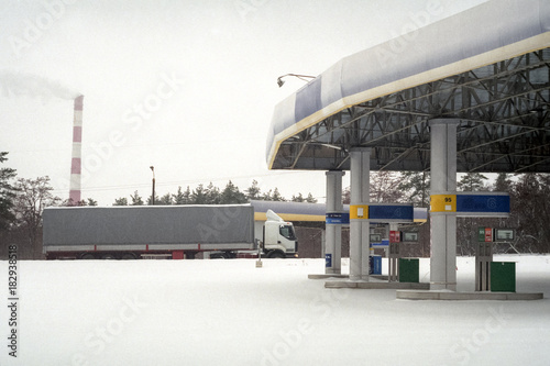 The truck passes by an filling station after an abundant snowfall. photo