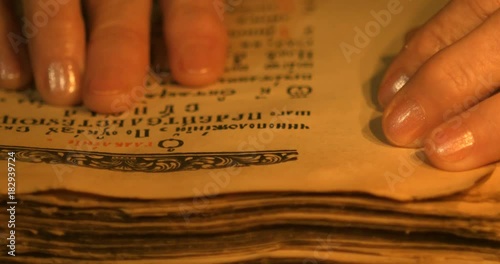 Elderly woman reading old book by candlelight