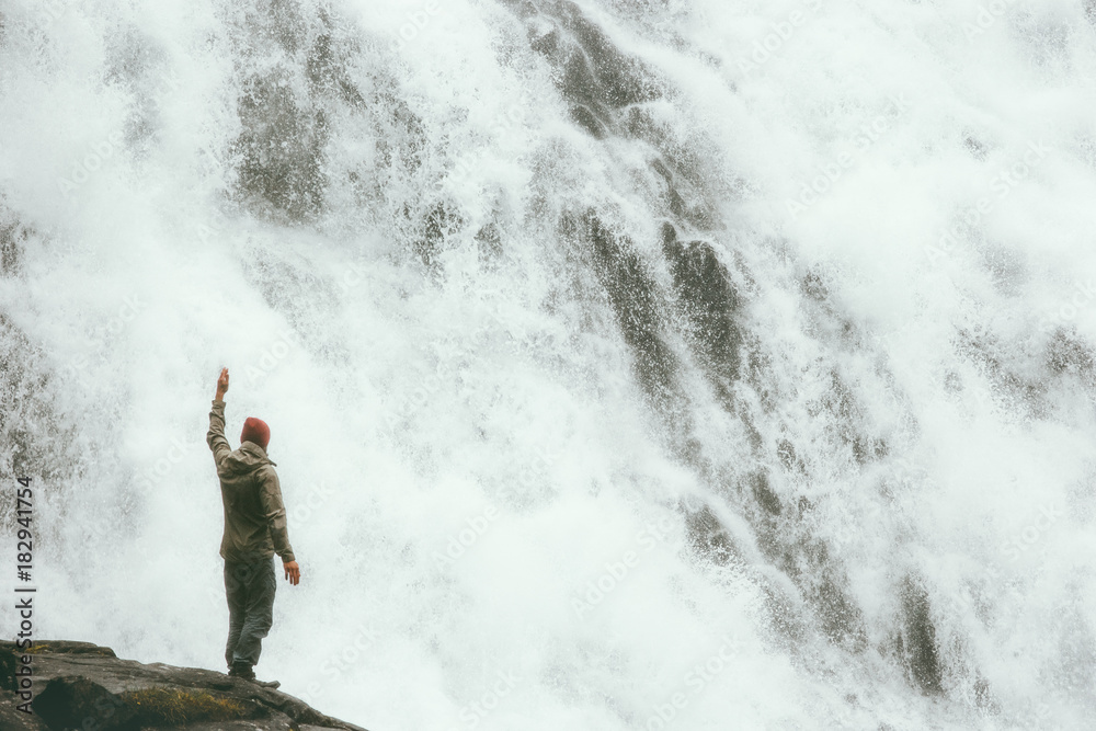 Traveler Man standing on cliff at big waterfall outdoor Travel Lifestyle success concept adventure scandinavian vacations power of nature Traveler Man standing on cliff at big waterfall outdoor Travel Lifestyle success concept adventure scandinavian vacations power of nature