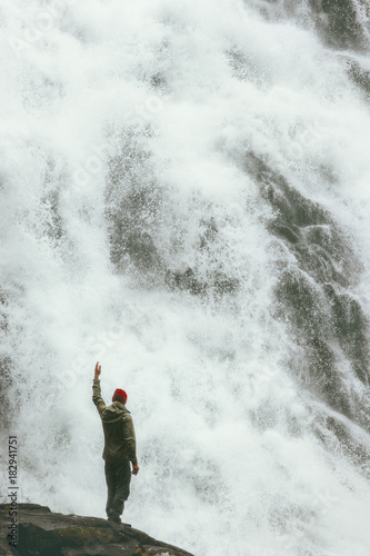 Happy Man standing on cliff at big waterfall outdoor Travel Lifestyle success concept adventure scandinavian vacations in Norway