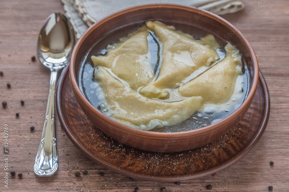 Dumplings kreplach in chicken broth in ceramic pots. National Jewish dish. Dumplings kreplach in chicken broth in ceramic pots. National Jewish dish.