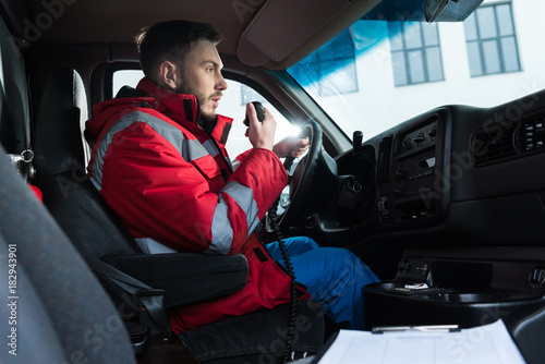 young handsome male paramedic talking by portable radio