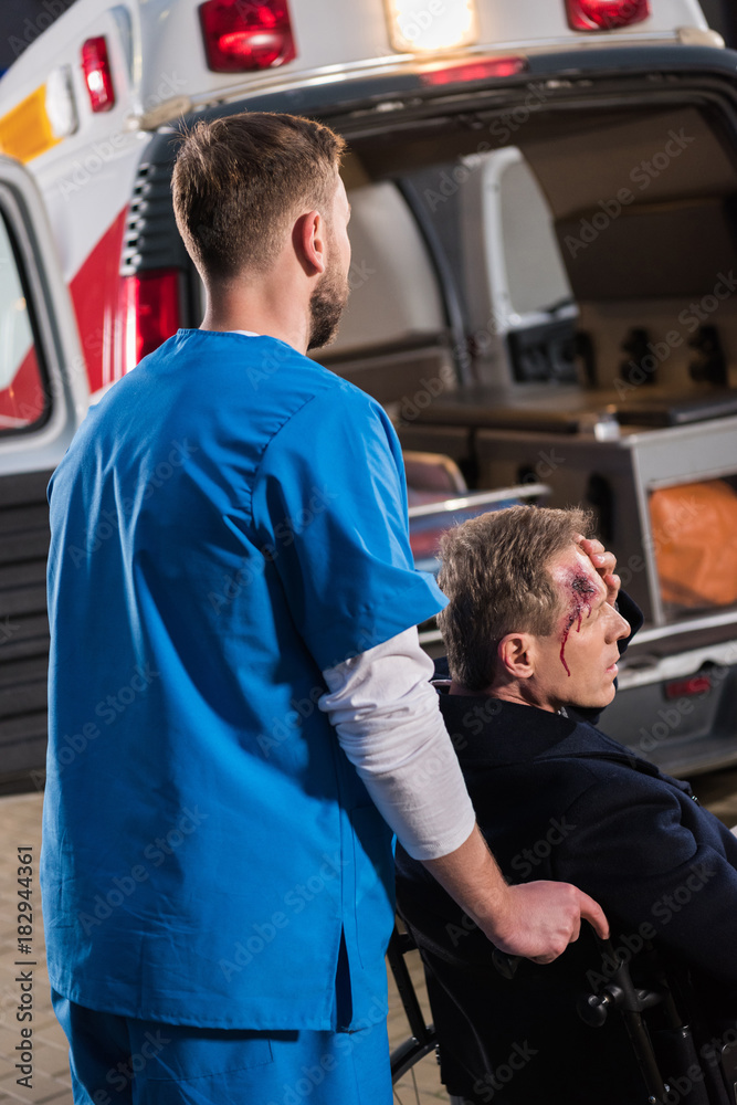 paramedic moving injured mature man on wheelchair to ambulance paramedic moving injured mature man on wheelchair to ambulance