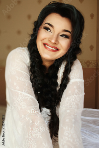 Smiling brunette woman looks happy sitting on the bed