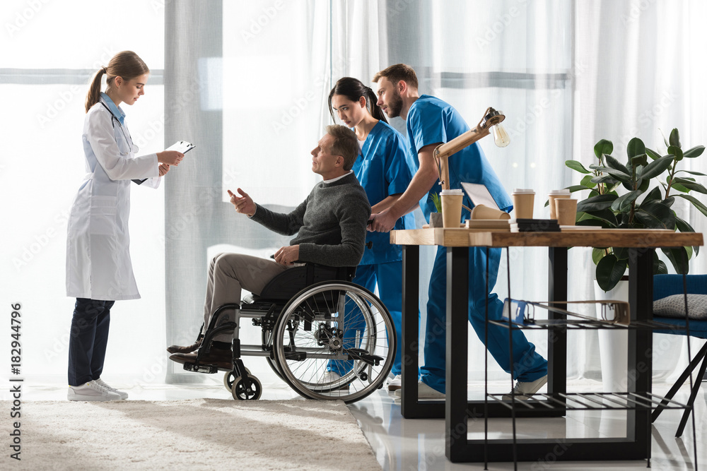 female doctor talking with middle aged patient on wheelchair female doctor talking with middle aged patient on wheelchair
