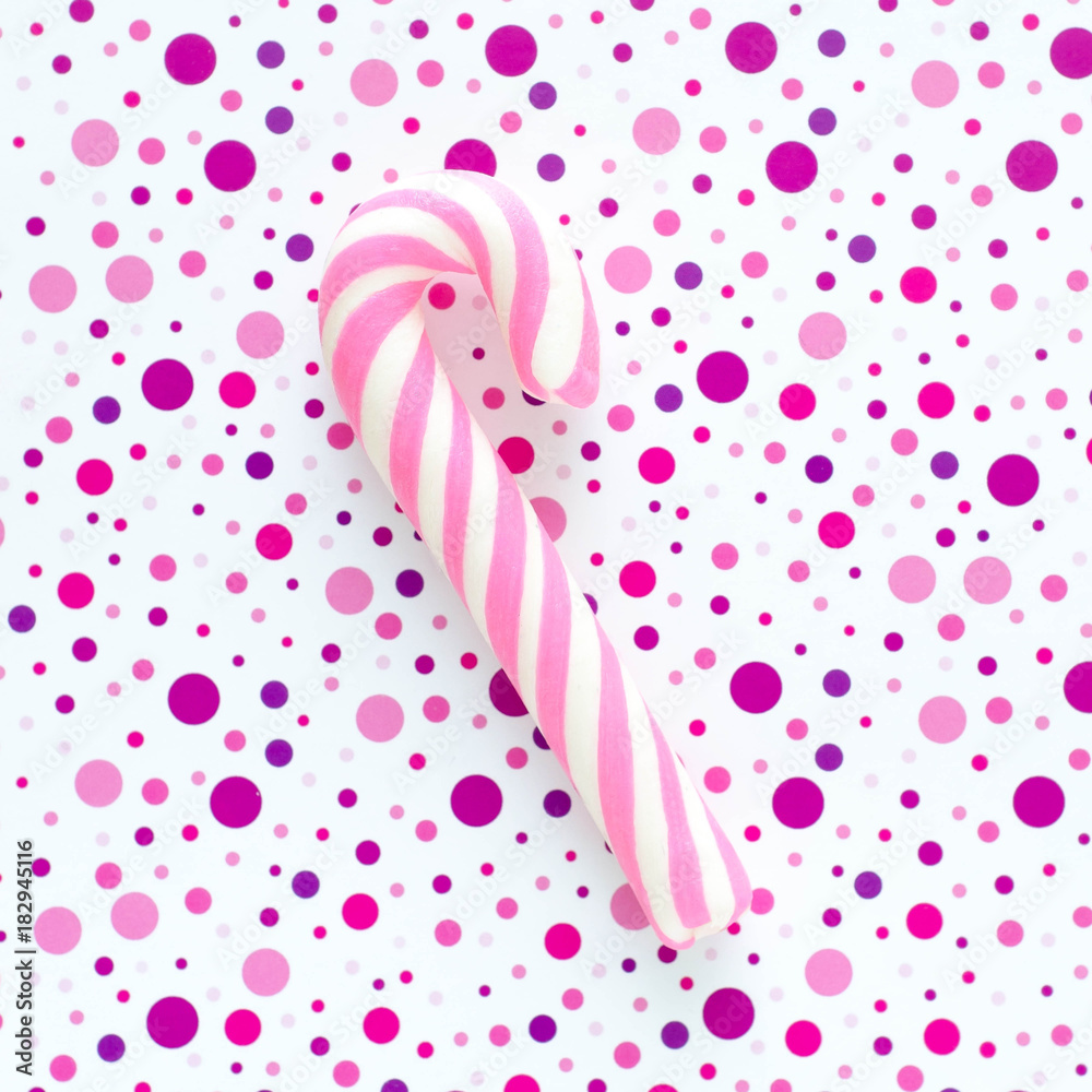 Pink caramel spiral stick on the purple dotted background