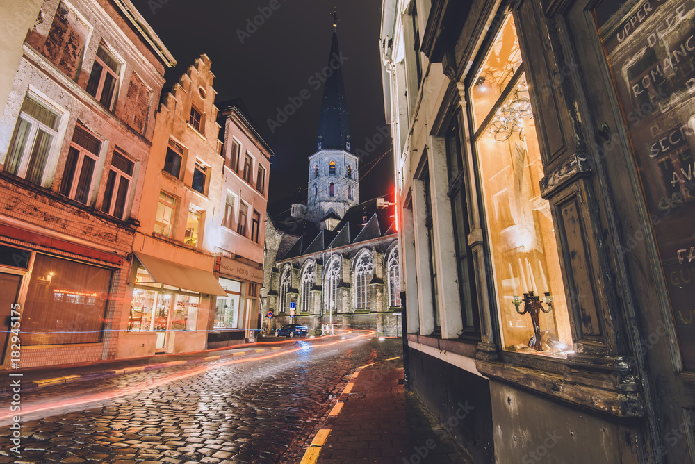 January, 3th, 2017 - Ghent, East Flanders, Belgium. Gent Old town by night with cobbled street view, merchant houses and gothic Saint James church also known as St. Jacob cathedral.