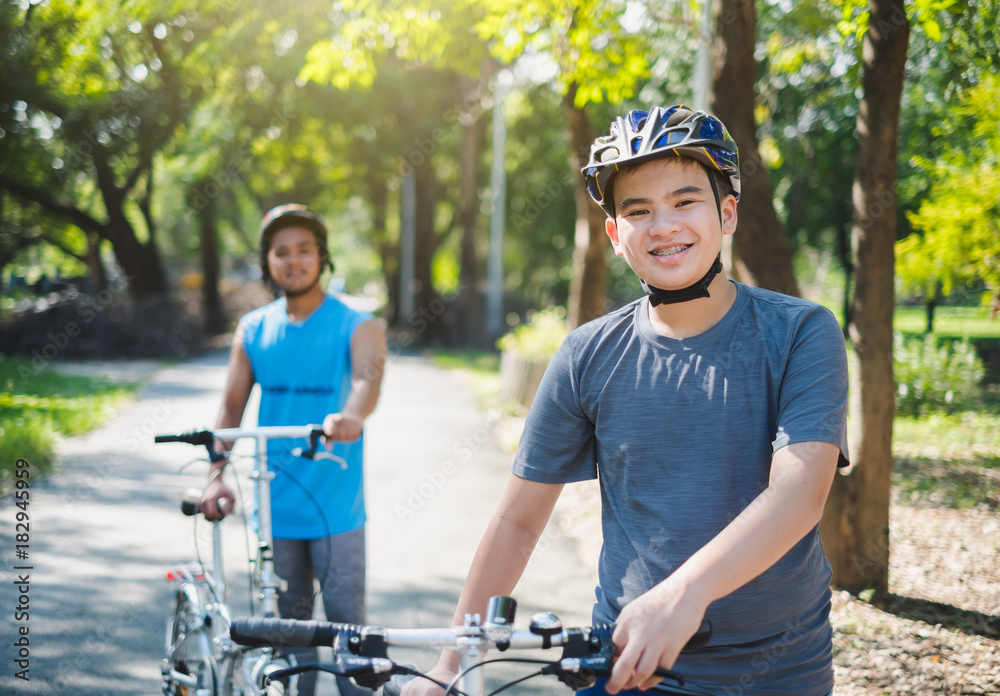 Obraz premium Asian boy with friend ride a bike/bicyle at outdoor green park in summer