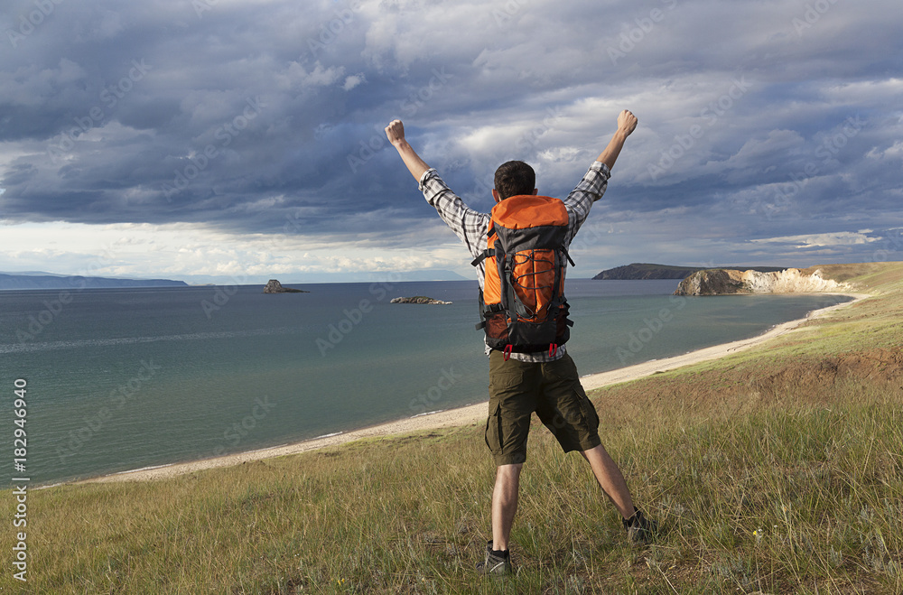 young tourist man with a backpack on the lake, Lake Baikal, summer tourist walk, freedom and happiness young tourist man with a backpack on the lake, Lake Baikal, summer tourist walk, freedom and happiness